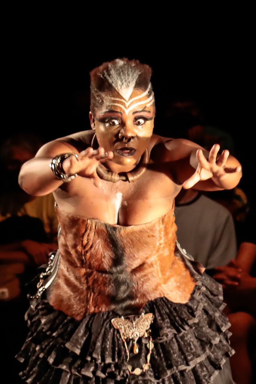 Performance photograph of Márcia Limma with arms outstretched, looking towards her hands.