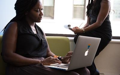 A professional in a black top sits at her laptop working