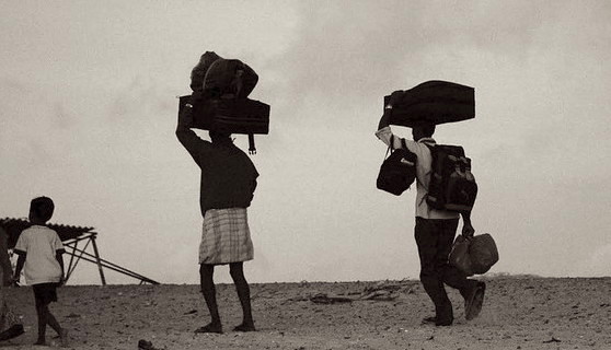 Photo of three migrants carrying their belongings