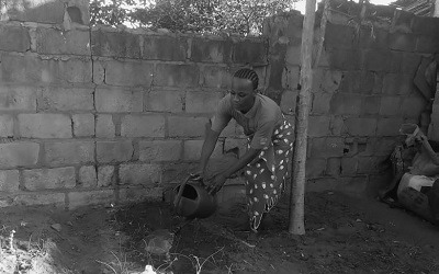 Photo shows a trans woman in Mozambique tending to her garden. She told us "Watering my garden to show society that transwomen perform all activities like other women in their home space. I call that positive visibility"