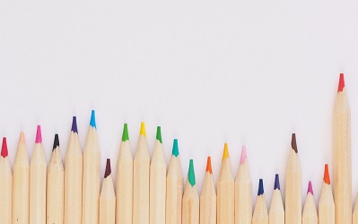 A colourful set of pencils lie on a white background