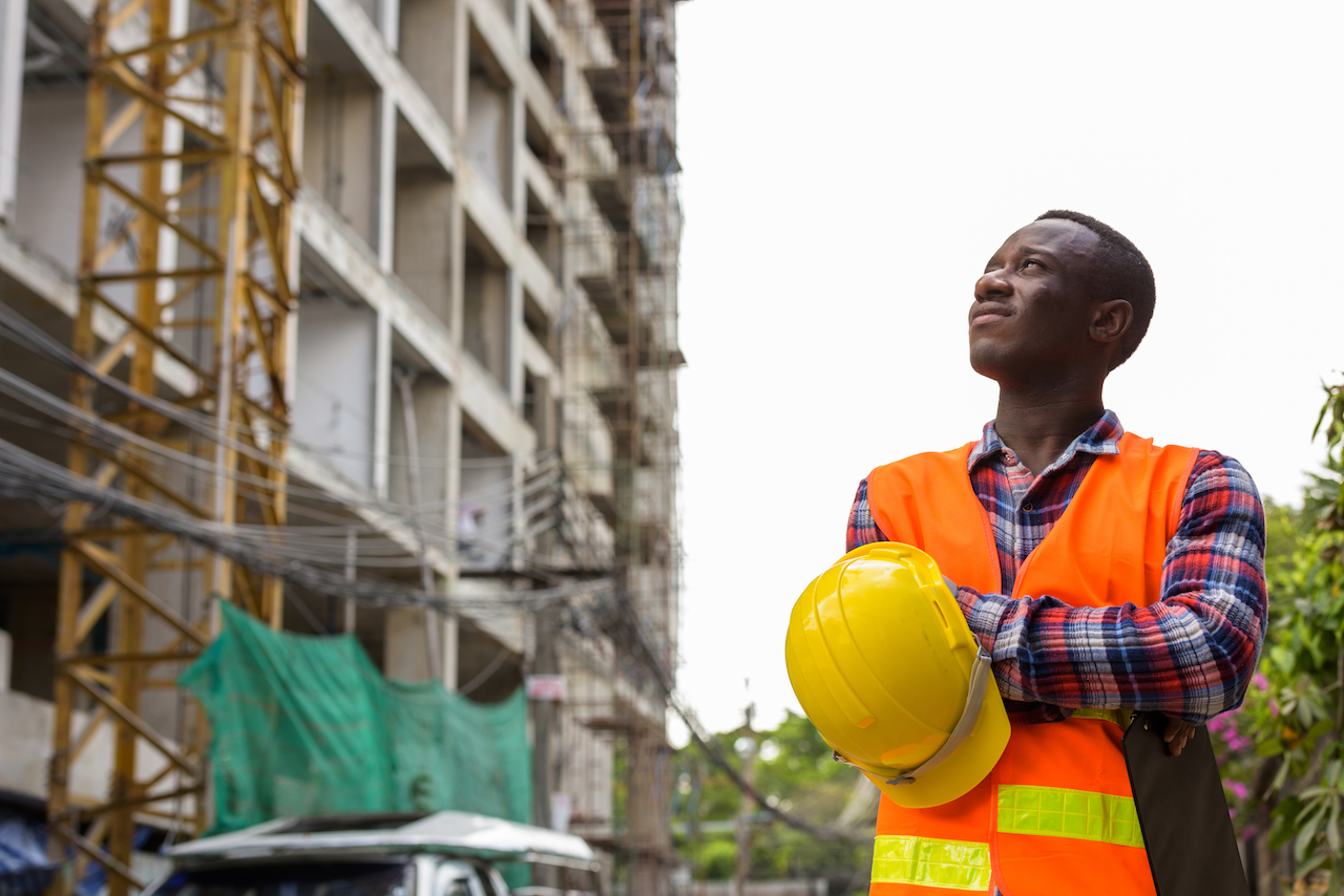 photo of construction worker looking up at building in progress