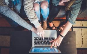 A group of young people learn around a laptop