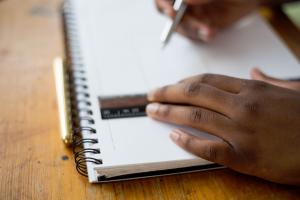 Photo of student's hands with ruler, pen and notebook