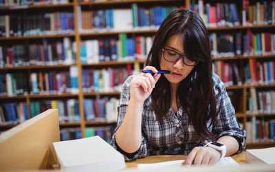 A girl reading notes at a desk in a library