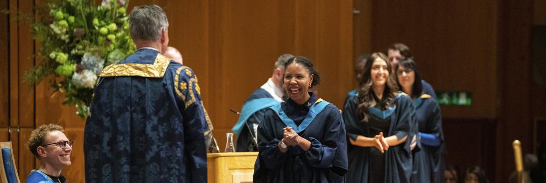 students smiling with joy as they cross the stage on the OU graduation day