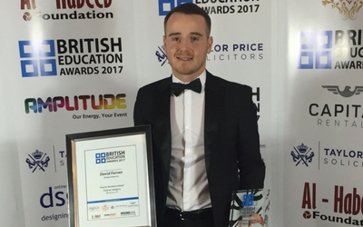 David poses for a photo wearing a tuxedo and holding a certificate and a trophy