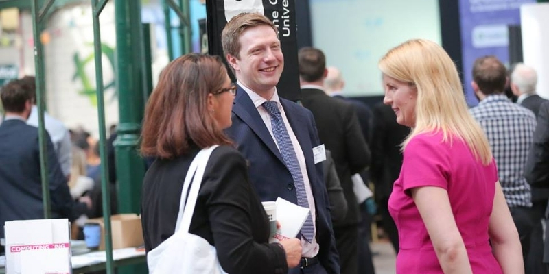 a group of three people standing chatting to each other