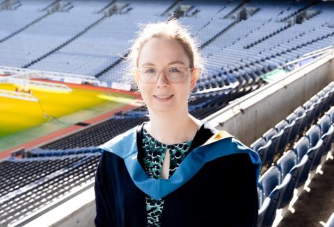 Aisling stands in her graduation robes smiling