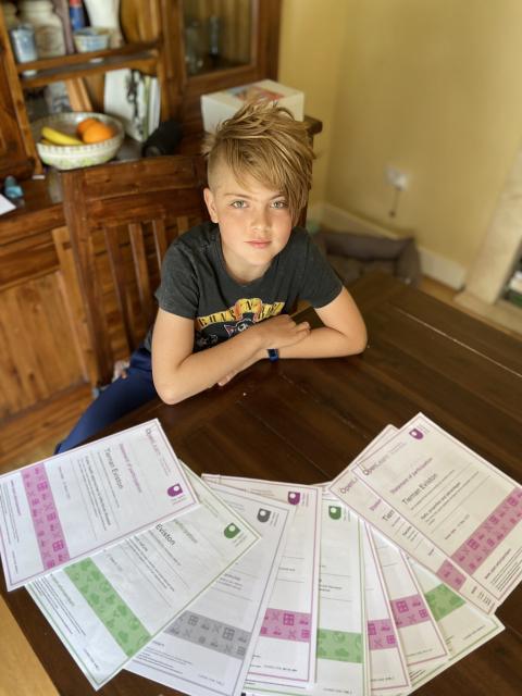 Tiernan sitting at a dinning room table with his OpenLearn certificates laid out in front of him