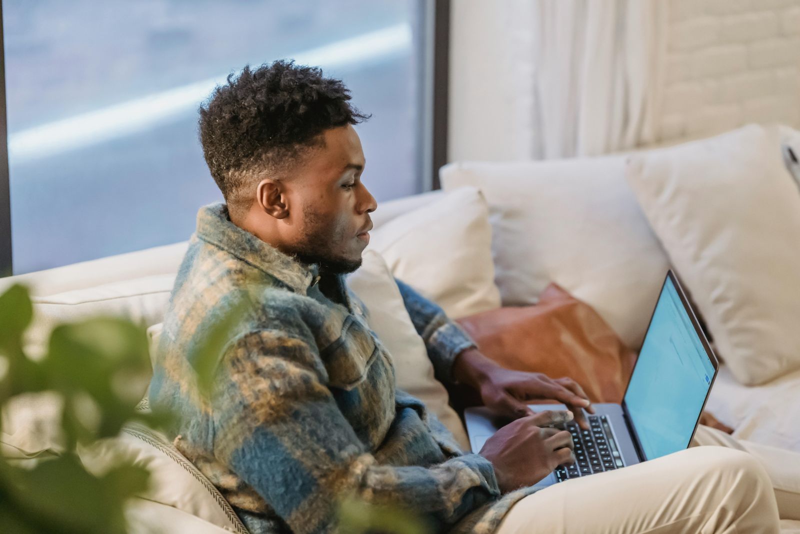 A person sitting on a couch using a computer. Photo by Andres Ayrton.