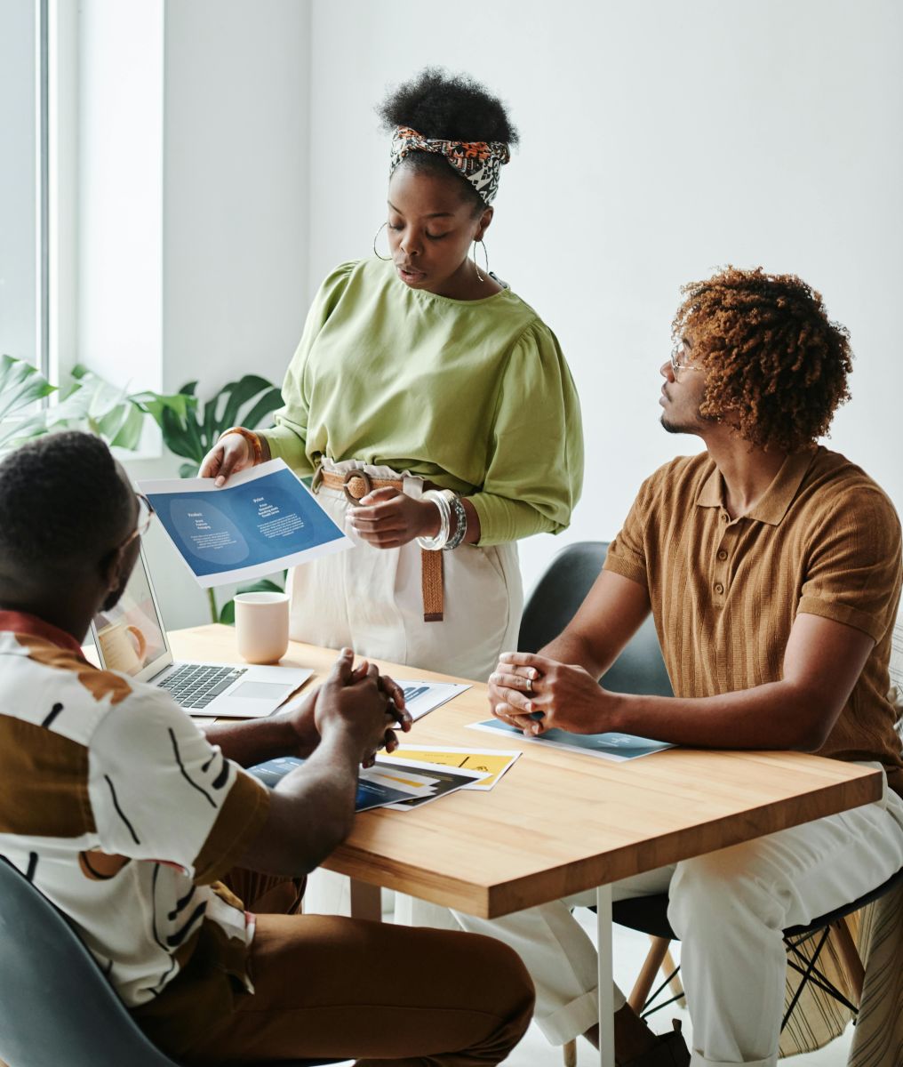 A person standing in front of a people sitting at a table, indoors. Photo by Darlene Alderson.