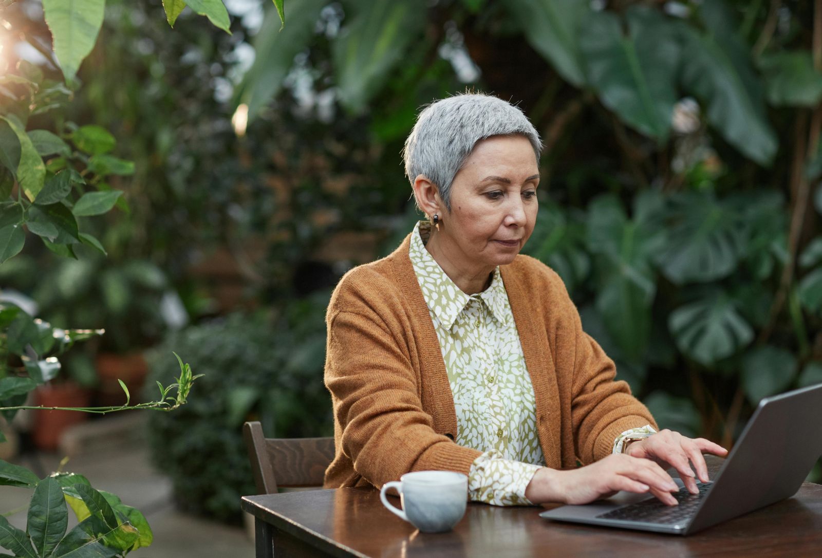 A person sitting at a table using a computer, outside. Photo by Marcus Aurelius.