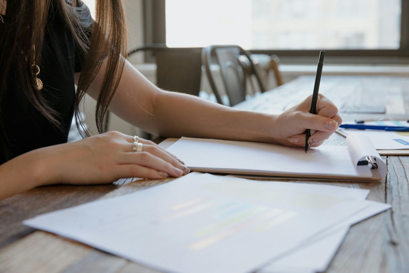 A close-up image of a person writing on a piece of paper. Photo by RDNE Stock project.