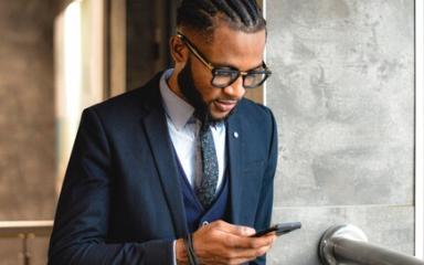 A smartly-dressed businessman is looking down at his phone