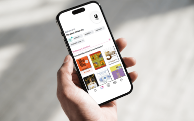 Hand holding a smartphone displaying a the Libby app with various book covers and categories on screen.