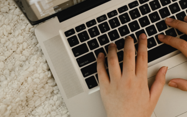 Close-up of a person's hands typing on an open laptop