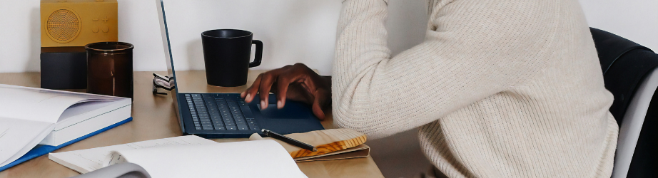 Male student working at a computer and making notes