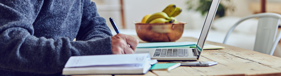 Student making notes from a laptop studying at home