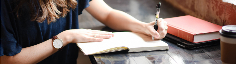 Student making notes with books in a cafe