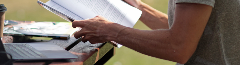 Student working outside at a laptop with a printout