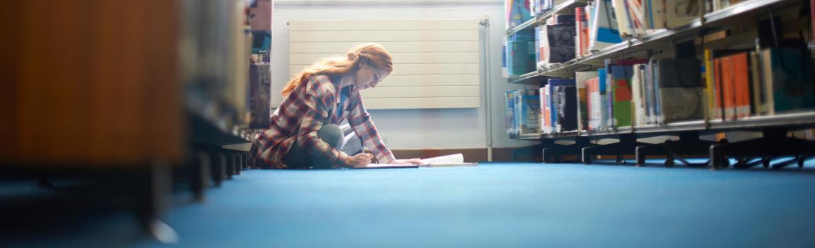 Student sitting on the floor in a library