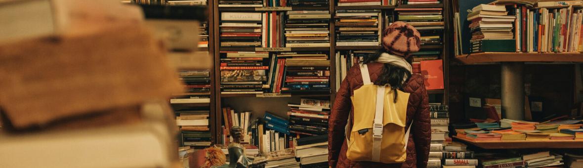 Someone browsing overfilled shelves of books