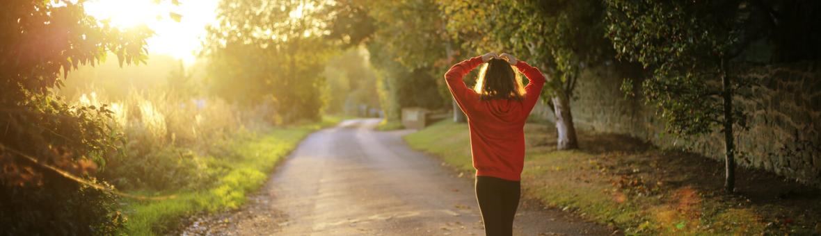 Someone in a red coat walking down a country lane