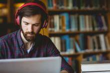 A man at a laptop in a library or study.