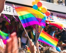 Pride flags and balloons can be seen at a busy Pride event