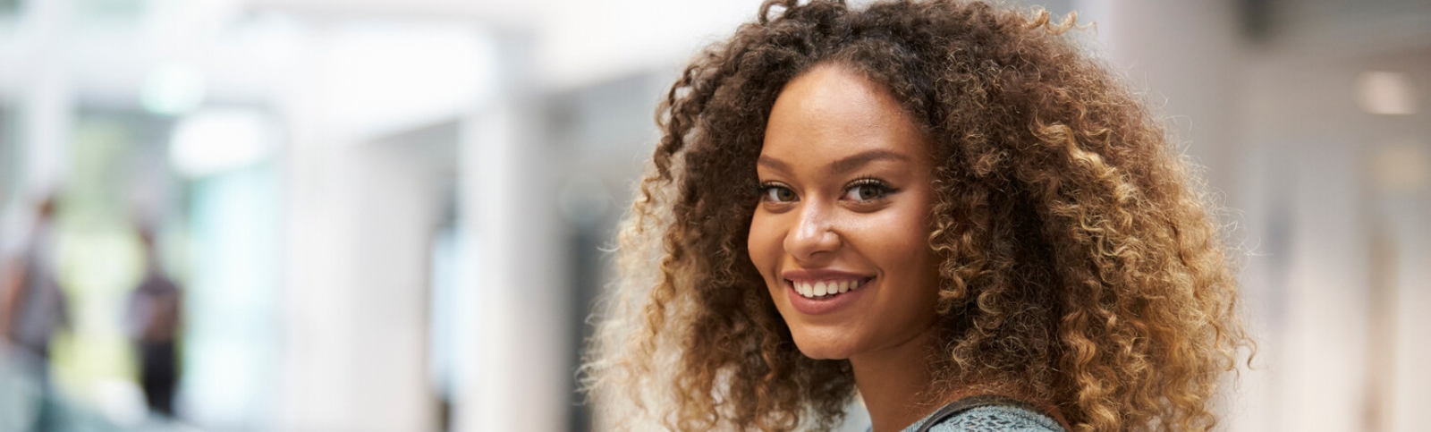 a girl with curly brown hair smiles into the camera