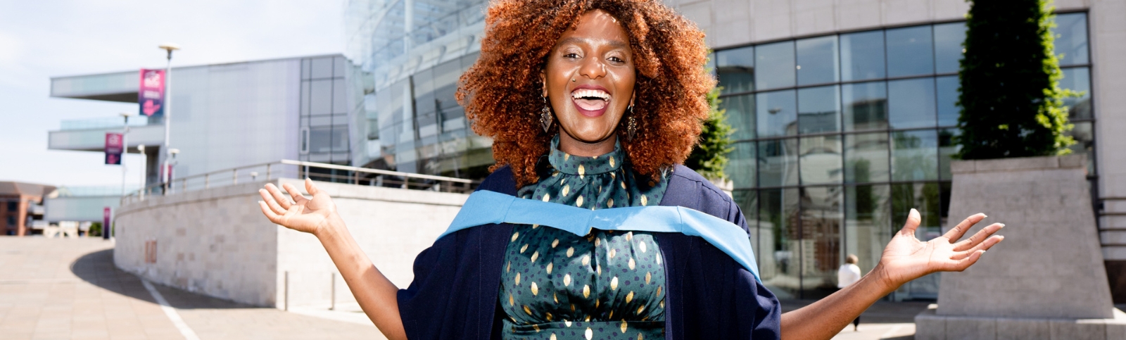 a female graduate celebrating with her arms up in her graduation gown