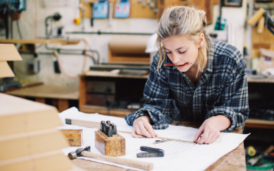 a women works at bench drawing on paper with some tools in front of her