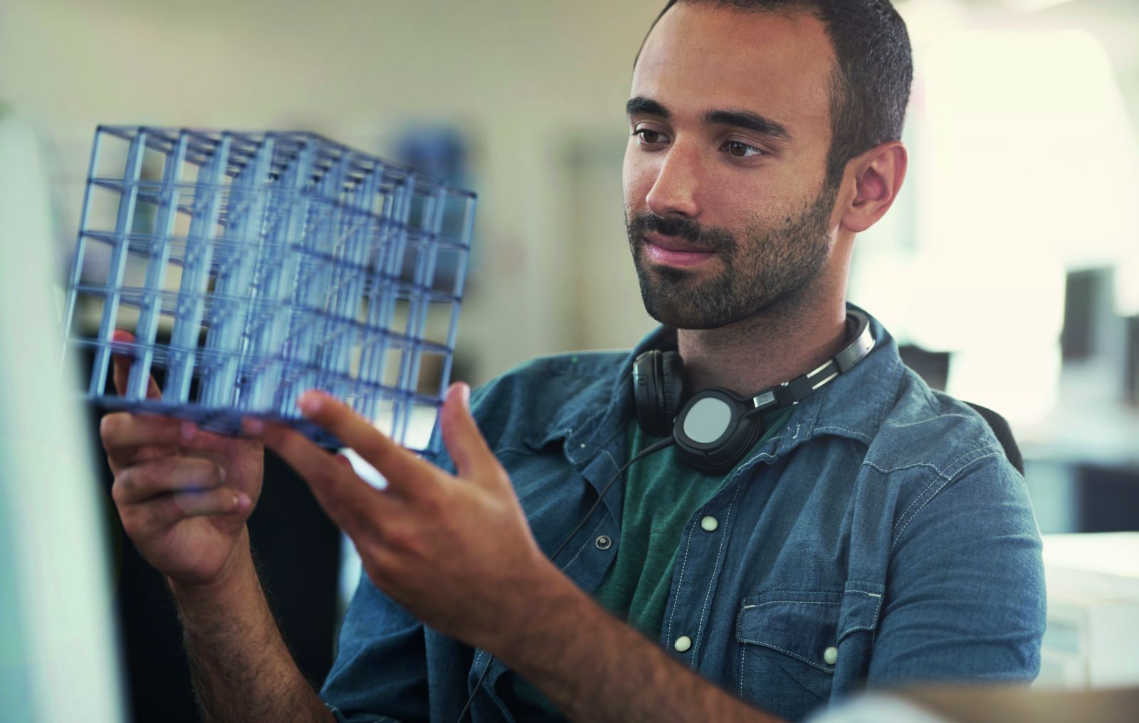 A young man looking at a glass cube structure in his hands