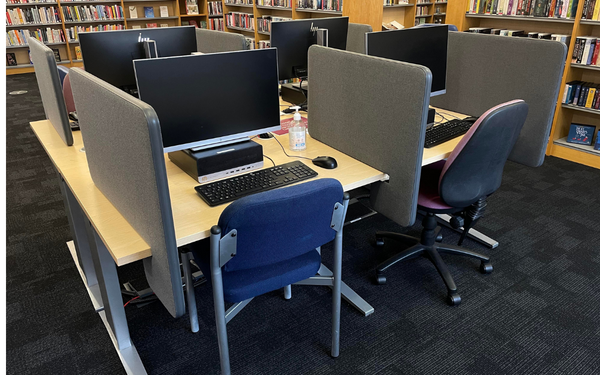 a set of computers in the middle of a library