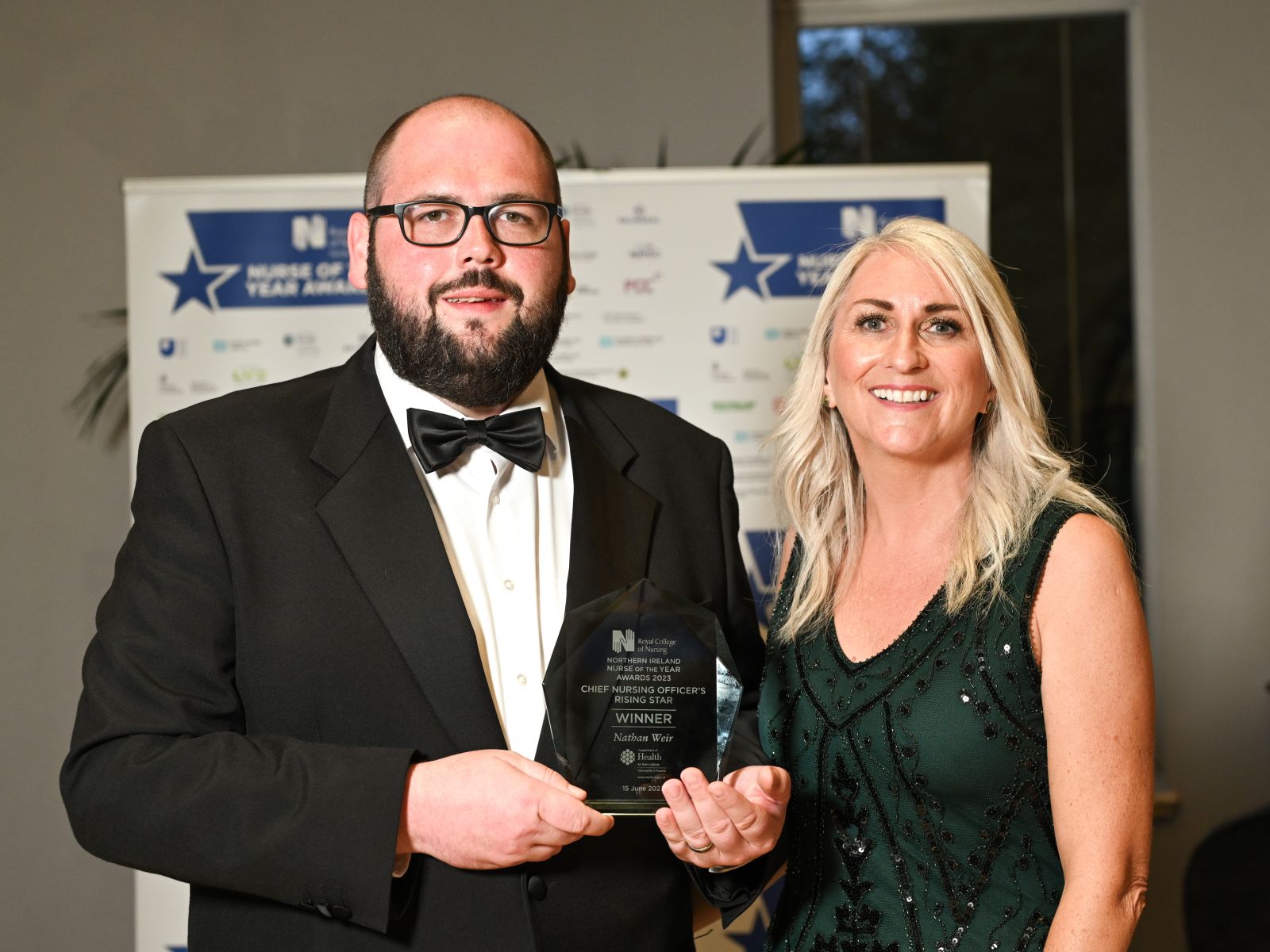 A man holding an award beside a woman in a green dress