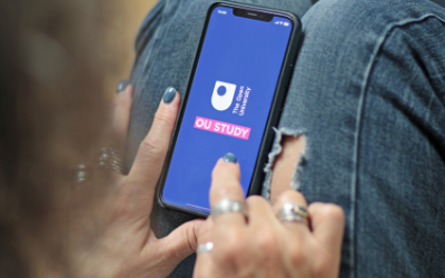 a girl looking at a mobile phone which has an OU study screen on it