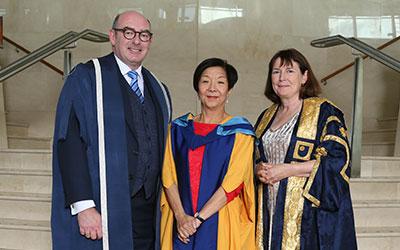 three people pose for a photo in their graduation robes