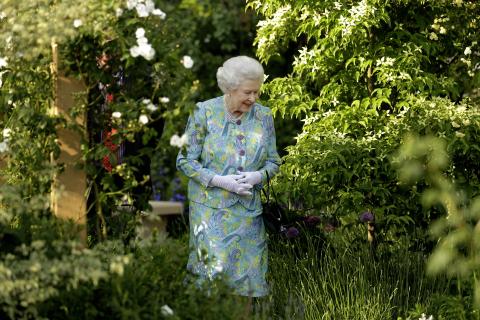 The Queen walking through a garden