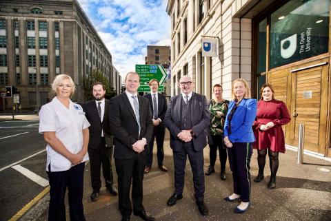 a group of people pose outside the OU offices for a photo