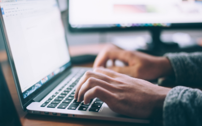 Two hands typing on a laptop keyboard