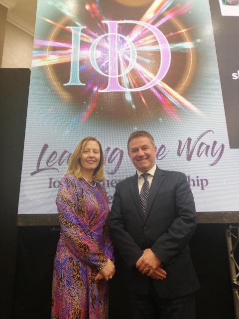 a woman and man stand an pose for a photo with the IOD branding behind