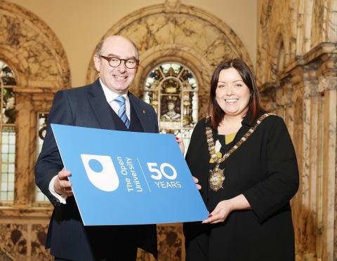 John D'Arcy and the Lord Mayor stand posing for a photo holding an OU 50th board