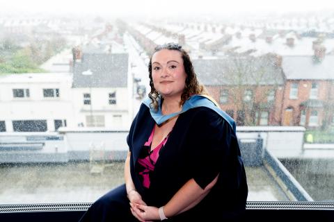 Joanne sitting and smiling to camera with Dublin city in the background.