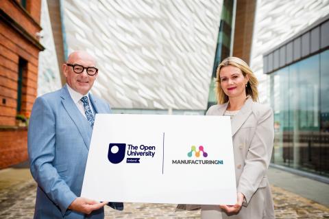 John D'Arcy and Mary from Manufacturing NI standing holding a board with the OU logo and Manufacturing NI logo