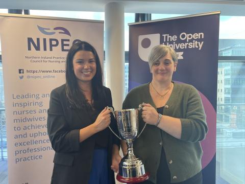 two nurses stand holding a trophy