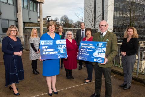 a group of people stand and pose for a photo, two of the group stand holding boards with NWRC logos and OU logos