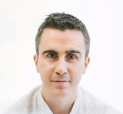 A photo of Patrick smiling to camera with a white background