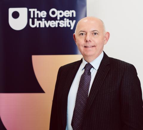 picture of Mark Durkin who is bald and smiling in front of an OU banner stand