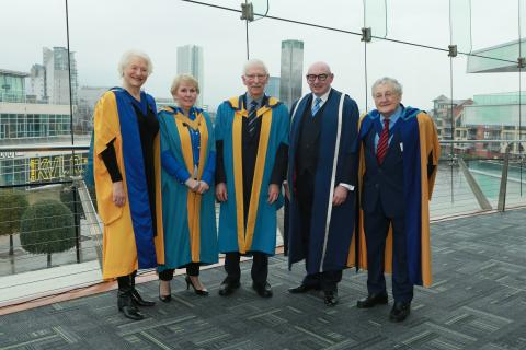 a group of people stand posing for a photo in the graduation robes